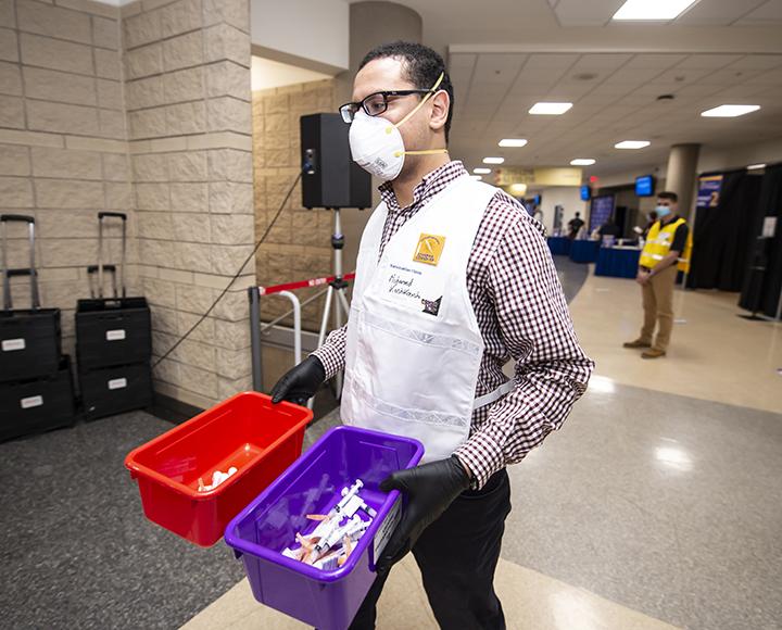 a person carrying two buckets of syringes