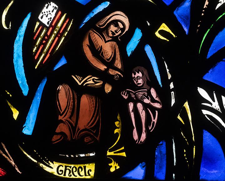 St. Dymphna holding a book with a child in colorful stained glass window