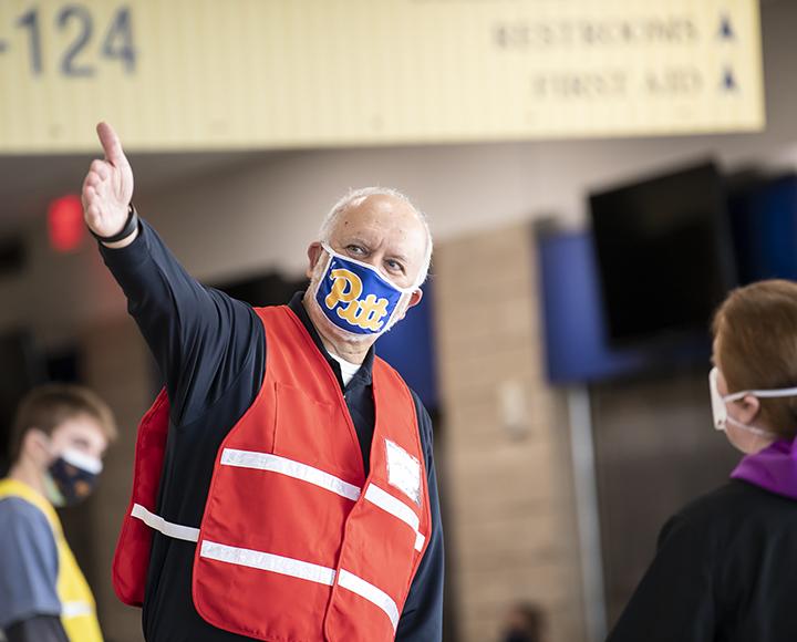 a man in a Pitt mask directing a patron