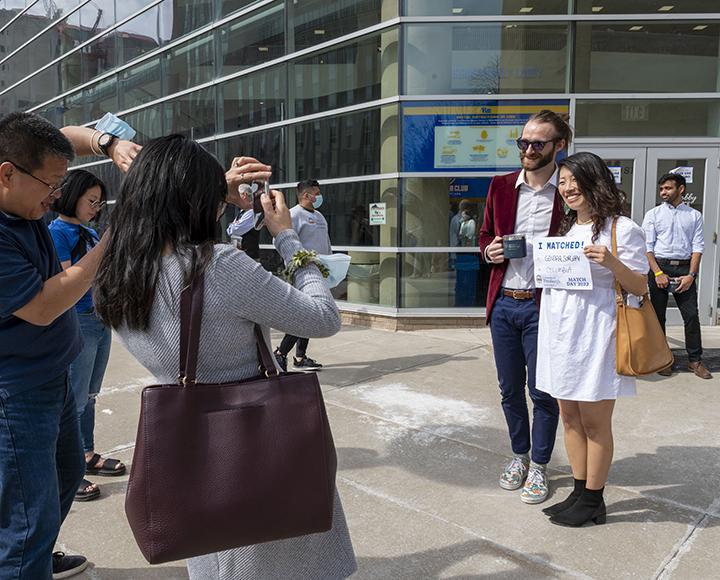 Two people posing for photos outside during Match Day