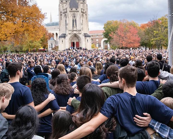 Crowd of people standing on lawn in front of Heinz Chapel