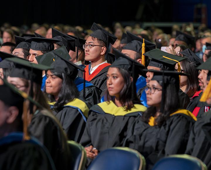 Graduating students standing near their seats during ceremony