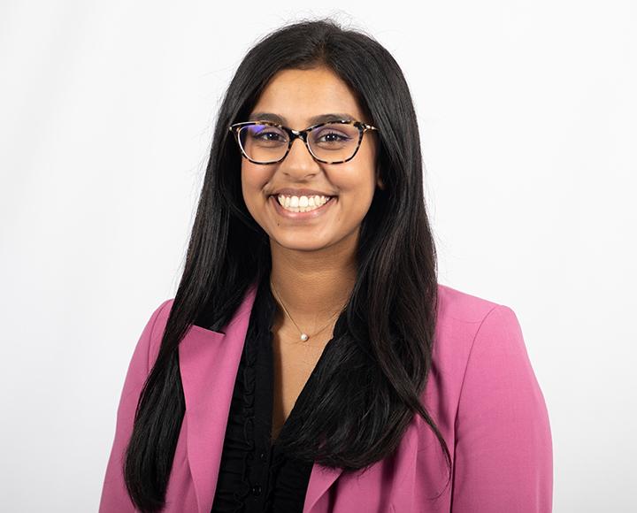 Aboli Kesbhat smiling in pink blazer in front of white background