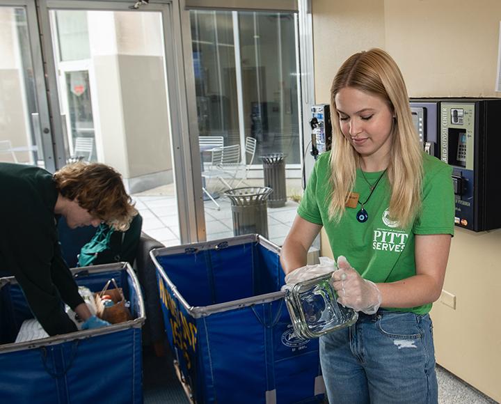 Woman cleaning glass jar next to bins with donated goods
