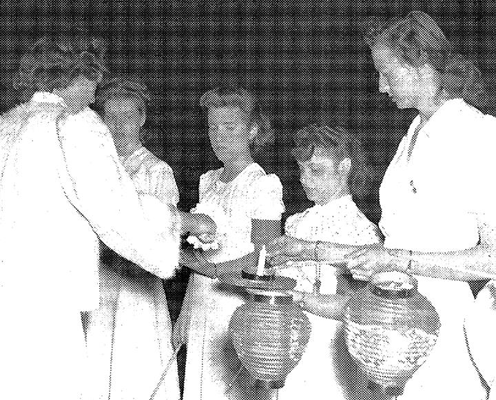 a black and white photo of women lighting paper lanterns
