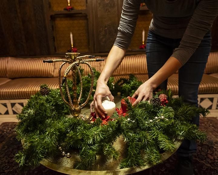 a person placing a candle in the center of a wreath