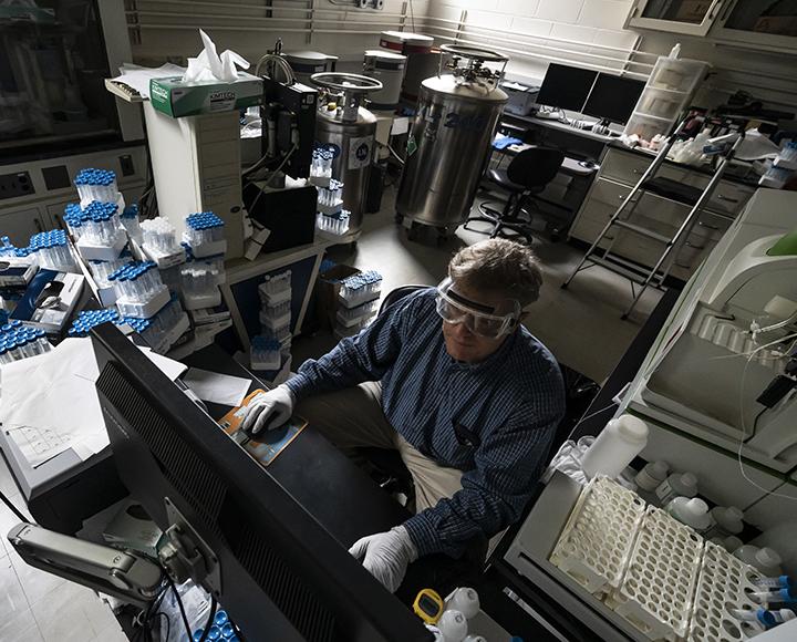 A man wearing googles uses a computer in a lab.