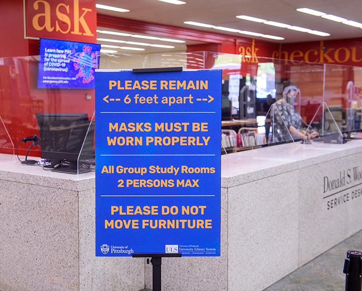 A sign in the Hillman Library promotes social distancing and masking