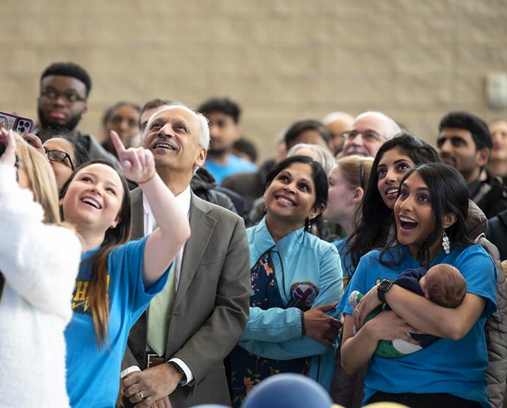 A crowd of people smile, point and look up