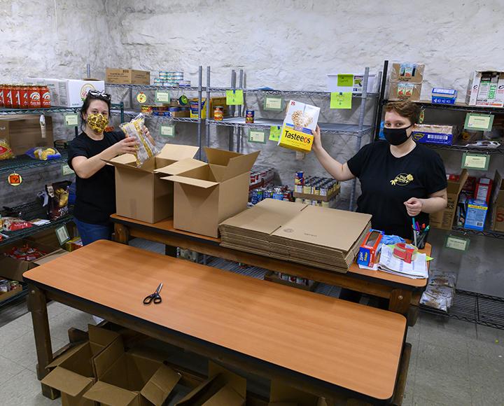 two masked people packing boxes of food