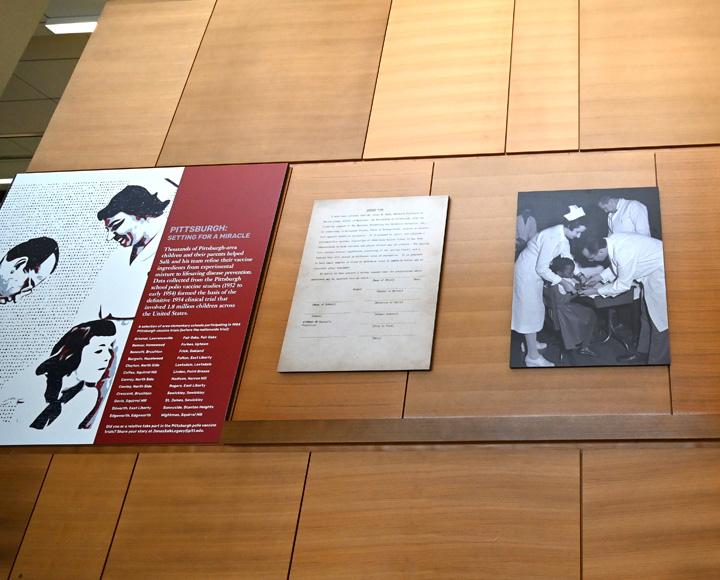 a wall with two photos of Salk and a document hung on it