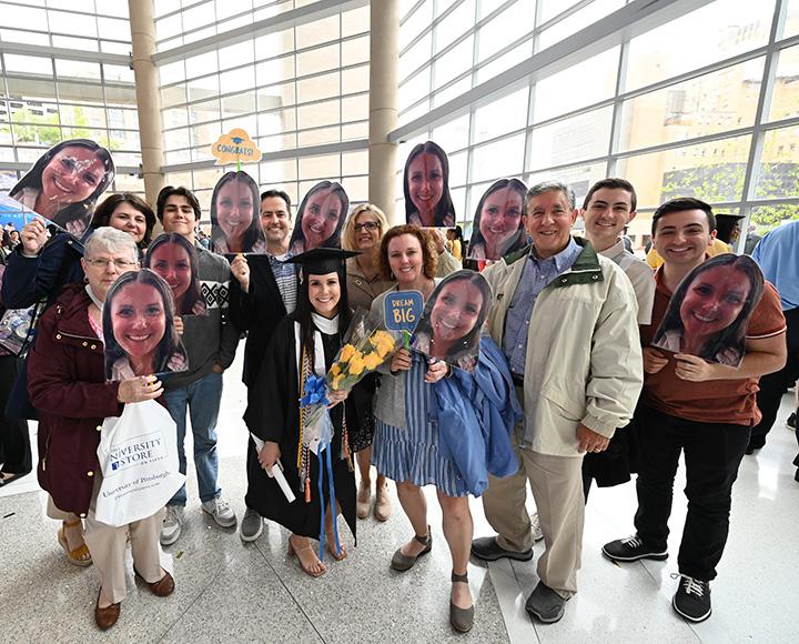A crowd of people, several holding cardboard cutouts of a girl's face