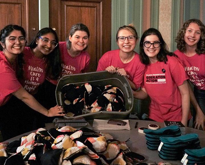 a group of students holding a bin of reusable period products