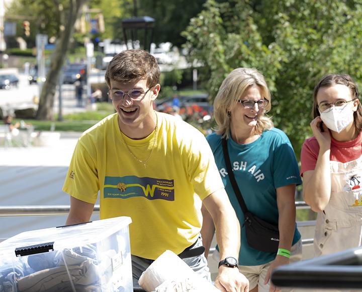 a student in yellow pushing a moving cart