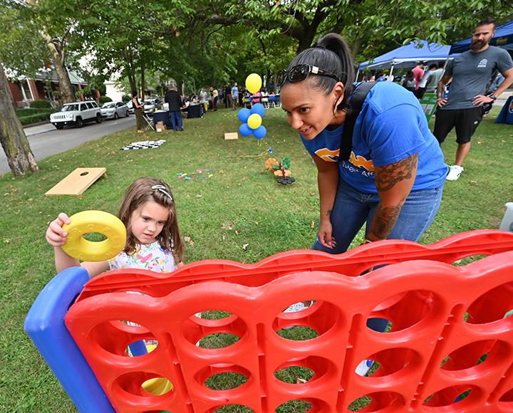 A child and adult play an oversized Connect 4 game outside