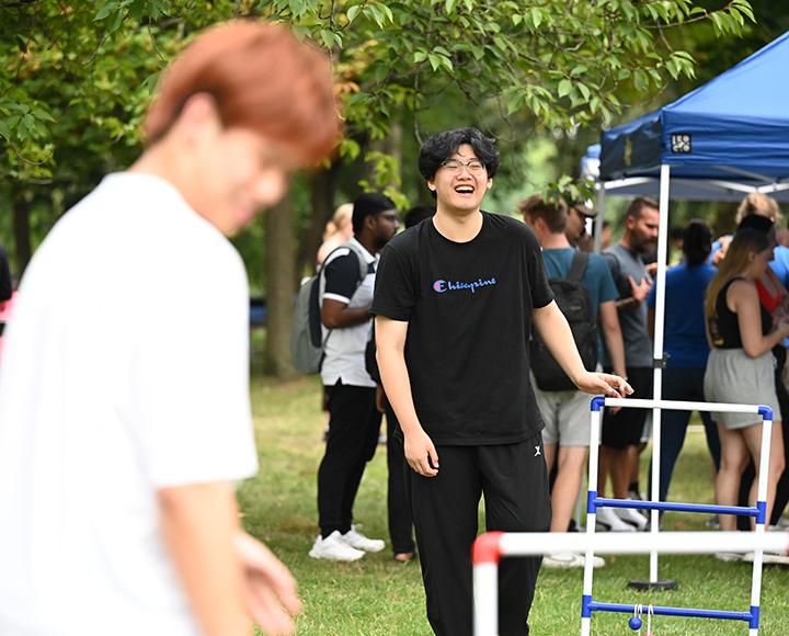 A person laughs while playing a game outdoors