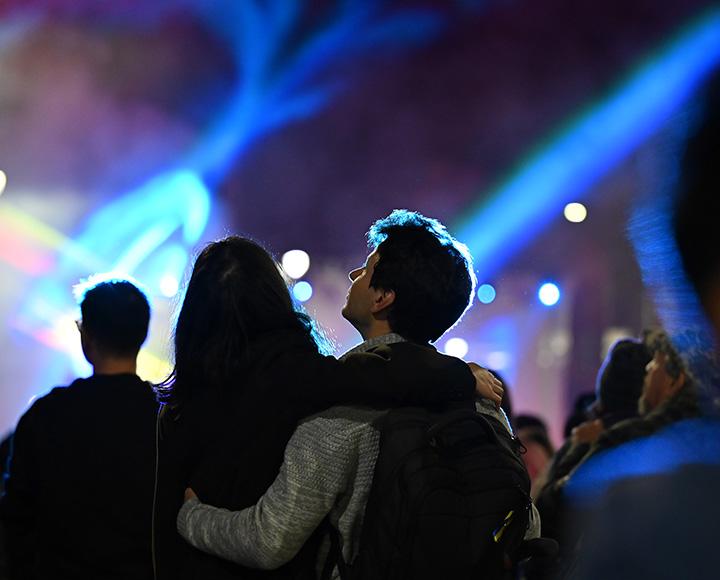 A couple watches lights beam in the darkness