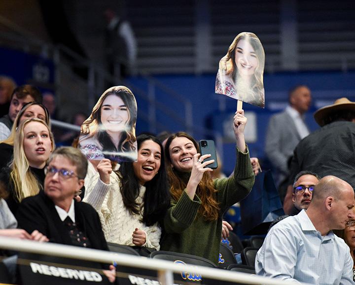Two people hold up cutouts of a girl's face
