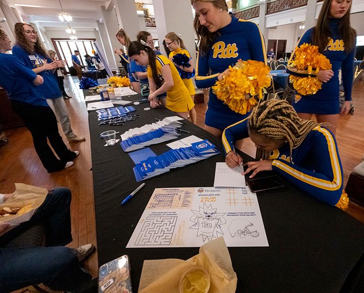 People kneel to write notes on a table filled with cards