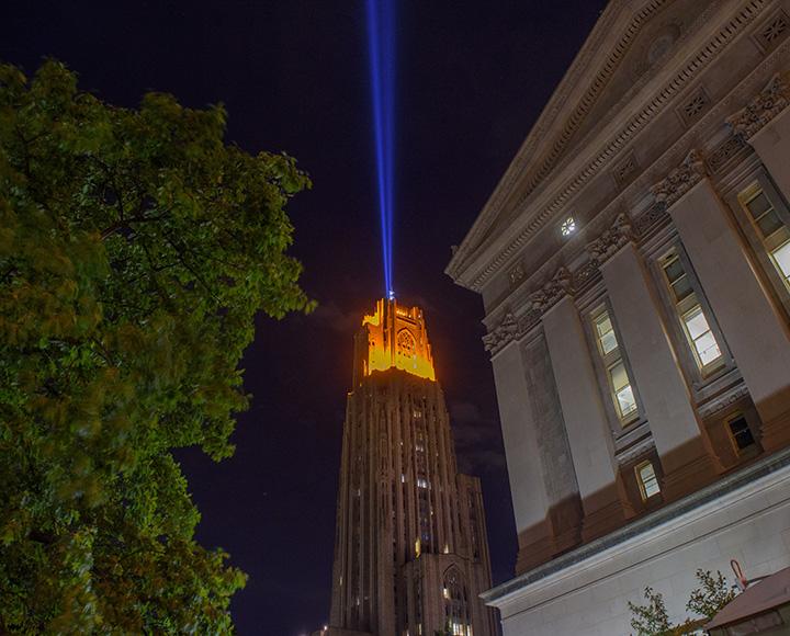 A column of light shines into the sky from the Cathedral of Learning