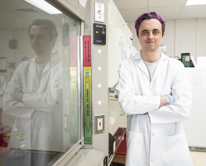 Zak Hutchinson poses next to a fume hood.