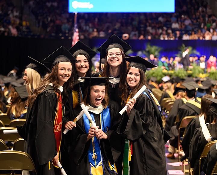 A group of graduates poses with their diplomas