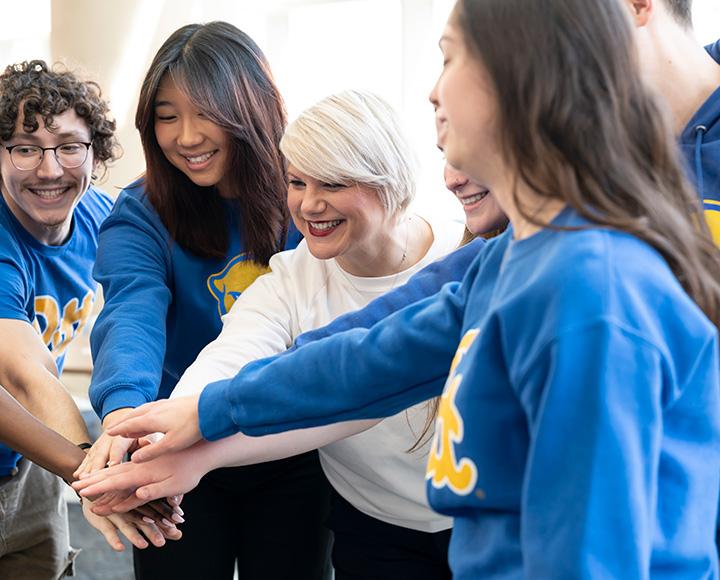 Panzella and students put their hands in for a cheer