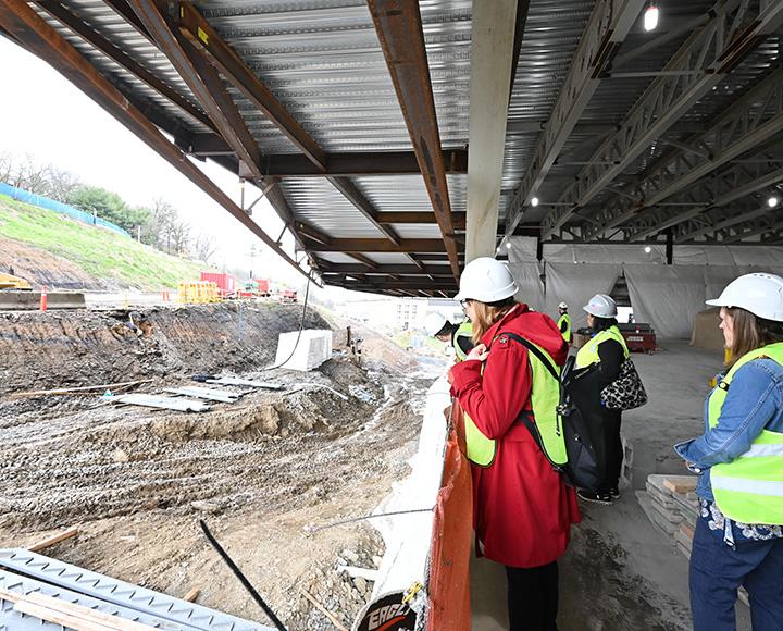 People in vests and hard hats tour a construction site