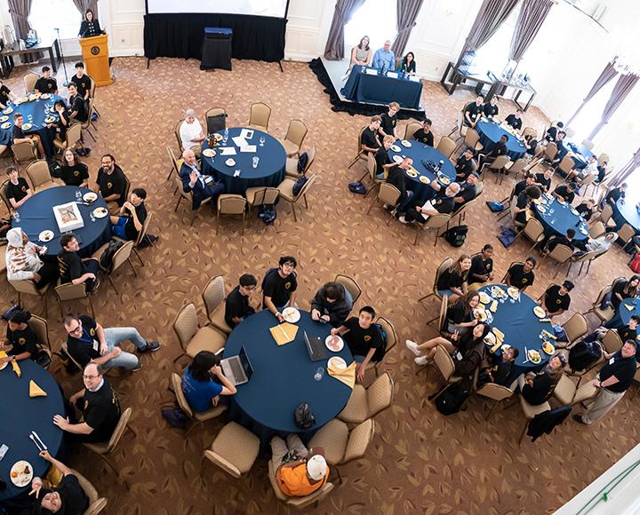 An aerial view of Pitt's CyberCamp participants sitting at tables.