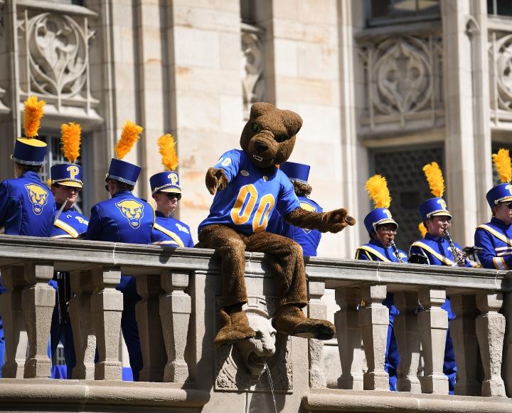 Roc the Panther sits on a stone railing of the Cathedral while the Pitt Band performs.