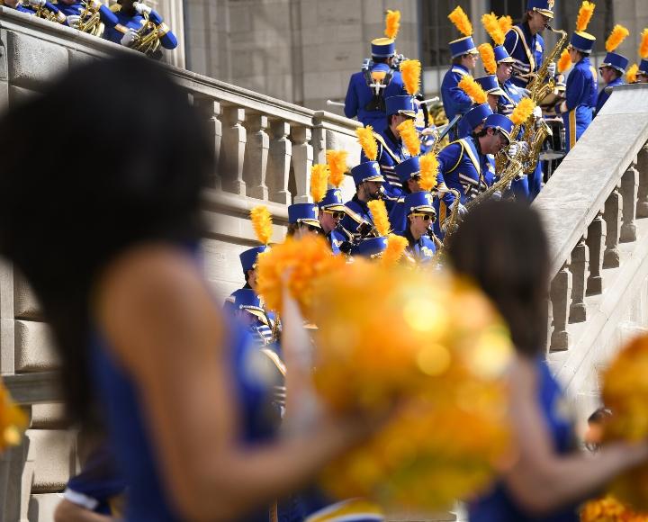Cheerleaders with pom poms are pictured with the Pitt Band while they do the 'snake' on the Cathedral steps.