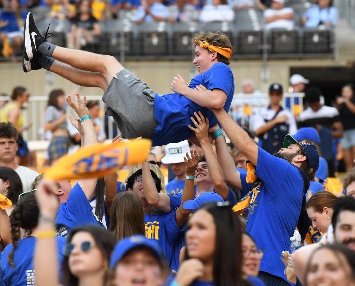 A Pitt student is held in the air by peers during the Homecoming game at Acrisure Stadium.