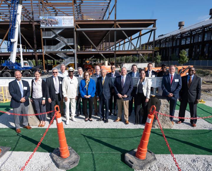 A crowd of people standing by a steel beam at a construction site