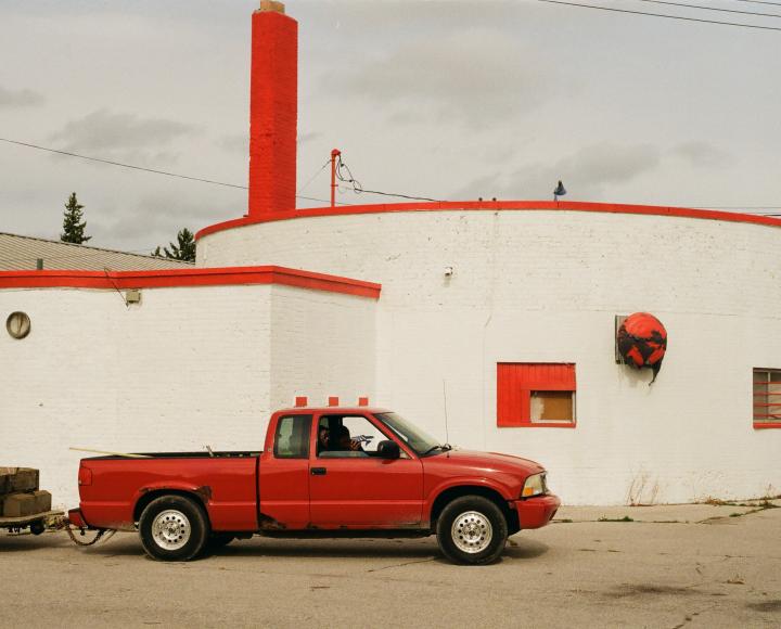 Doyen's photograph of a red truck set against a white structure with red accents and trim.
