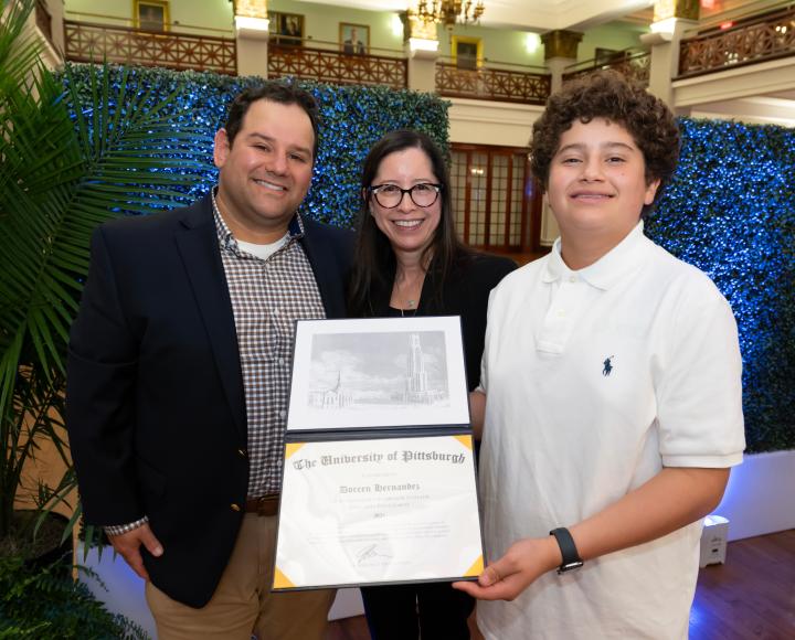 A winner holding a certificate with two people by her side