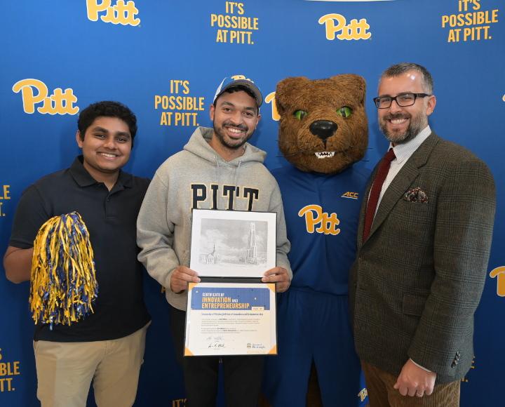 Pitt startup founders pose with Roc the Panther in front of a Pitt-branded backdrop