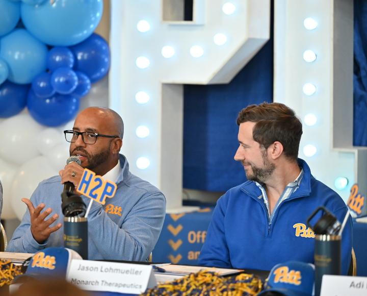 Innovators wearing Pitt gear talk about their startups, with light-up letters and ballons in background