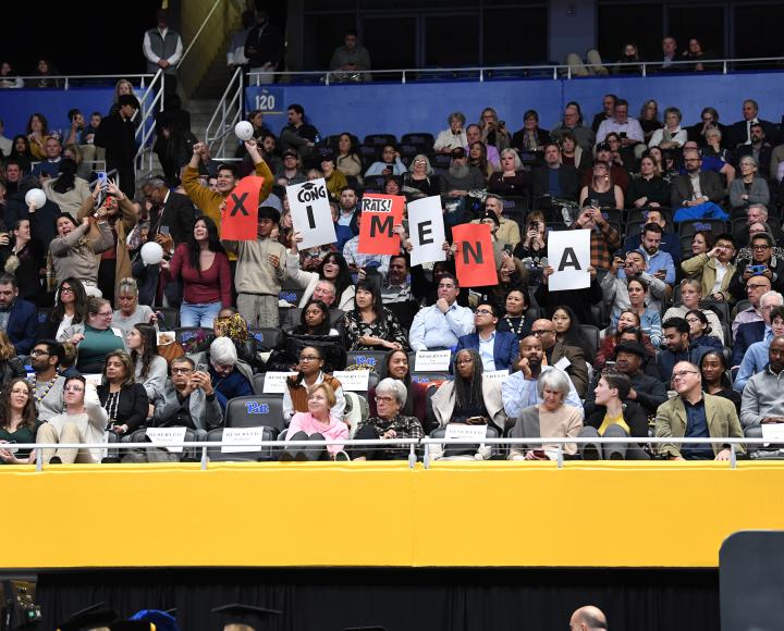 A family in the audience holds signs reading, "Congrats! XIMENA."