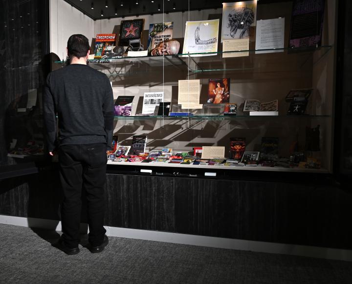 A person faces away from the camera, looking into a glass display case of props.