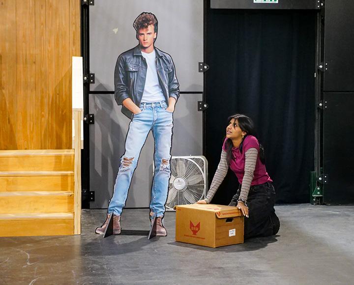 An actor holds a cardboard box while gazing up at a celebrity cut-out