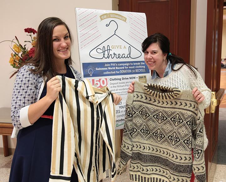 Students holding up clothes in front of a "Give a thread" sign