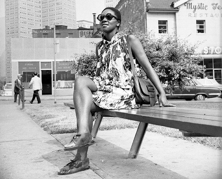 A girl in a dress sits on a bench.