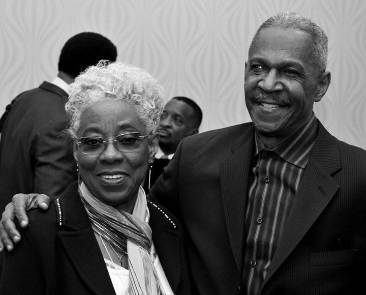 Two people in professional clothing pose in a black and white photo.
