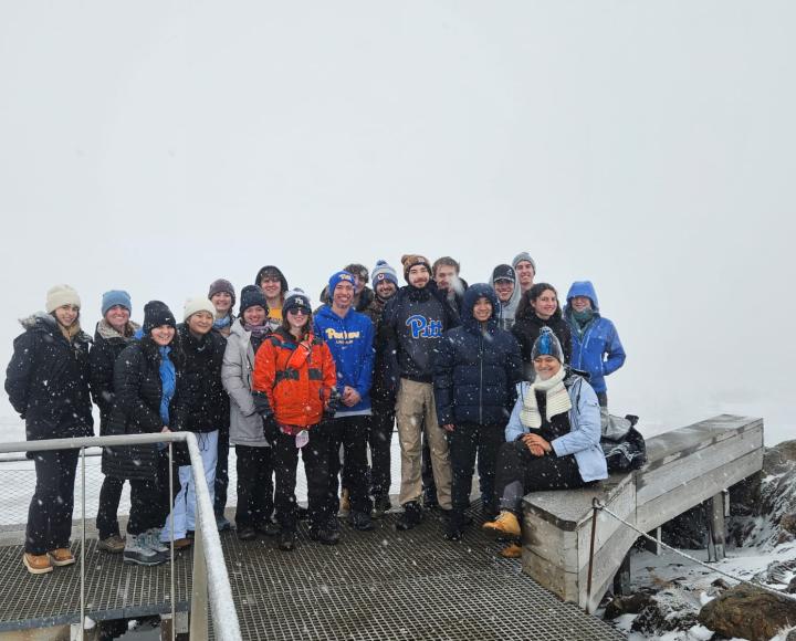 A group of students stand on a snowy bridge.