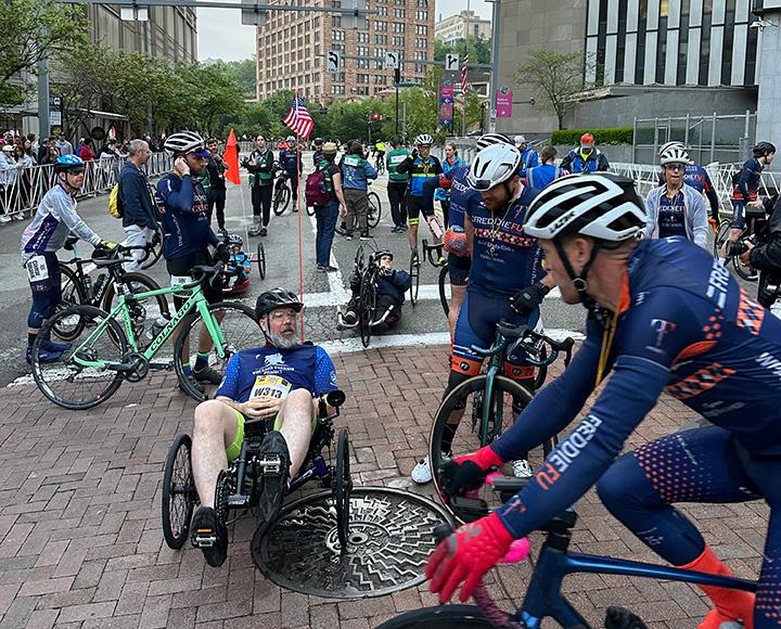 Two cyclists talk to a hand cycle racer by the marathon course.
