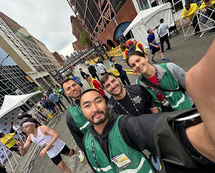 A group of volunteers in green vests take a selfie.