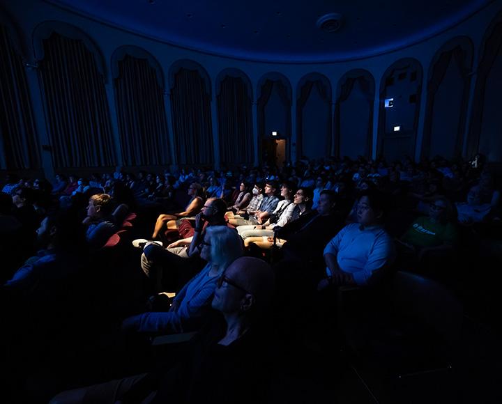 Attendees in audience look forward