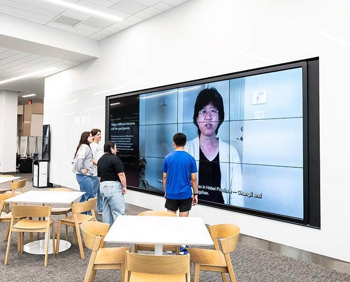 Students stand in front of the Digital Research Wall