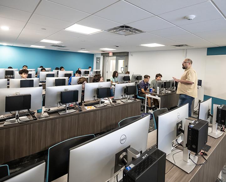 Wide shot of a computer lab where multiple students are instructed