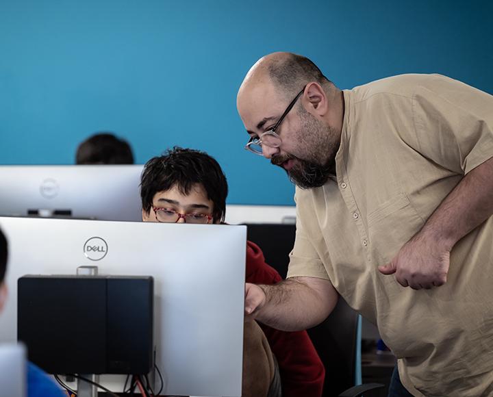Ahmed Ibrahim points on a computer as he instructs a student